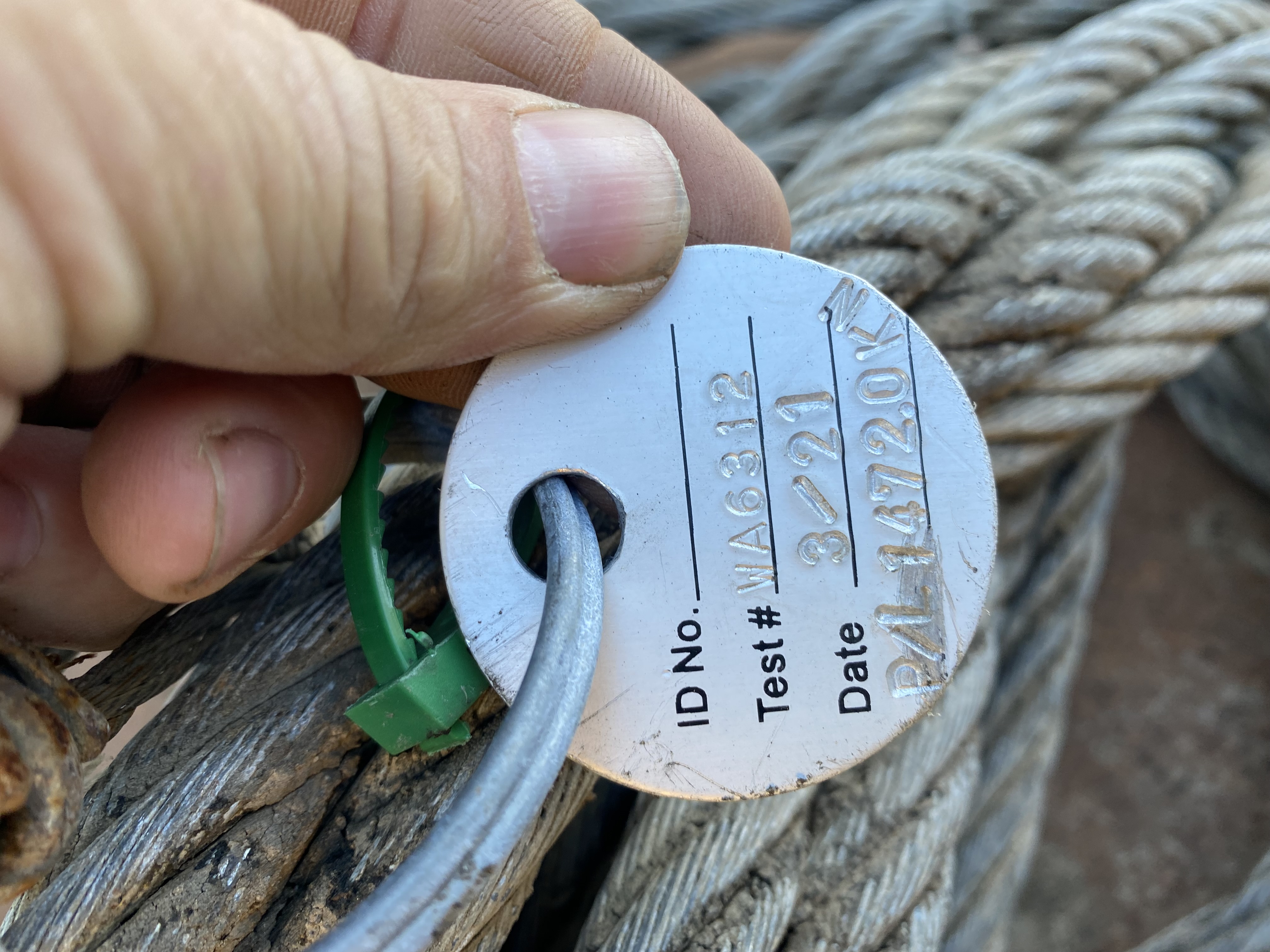 Close-up field inspection photo of a tag and wire rope